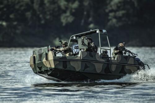 Łódz militartna na wodzie, z żołnierzami, z ciężką bronią.