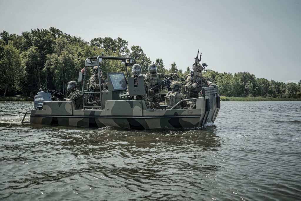 Łódz militartna na wodzie, z żołnierzami, z ciężką bronią.