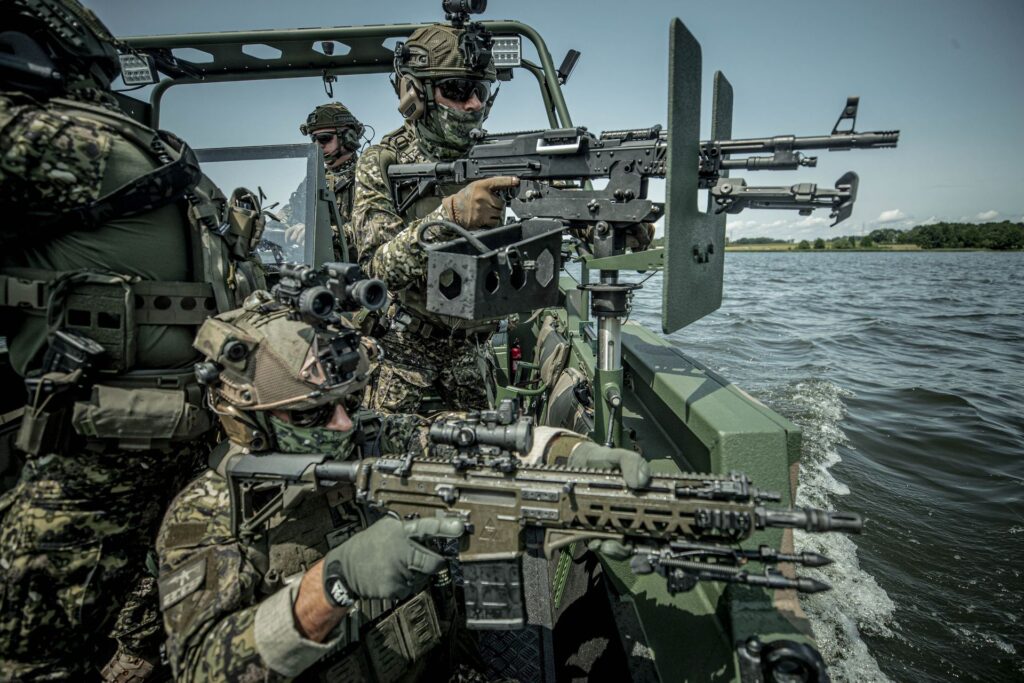 Łódz militartna na wodzie, z żołnierzami, z ciężką bronią.